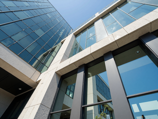 Professional corporate office building exterior with modern architecture, green landscaping, bright daylight